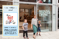 A woman and two young boys exit the National Civil War Centre. They are smiling and the two boys are holding toy axes aloft as one pretends to charge fiercely. The image also contains the Kids in Museums Family Friendly Museum Award sticker with the words Shortlisted 2024.